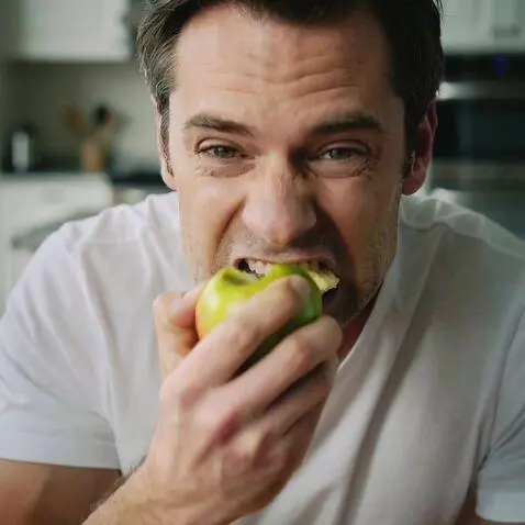 AI Video from prompt: generate a man biting into an apple, his face co