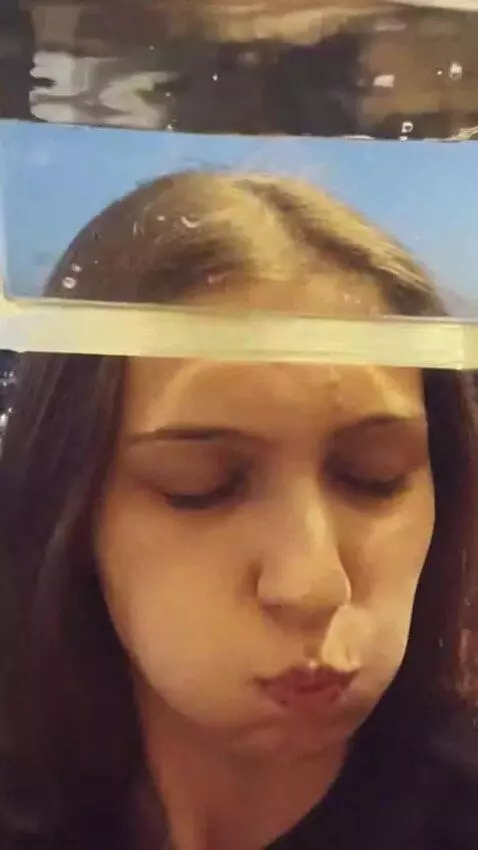 AI Video from prompt: The girl puts a transparent box of water on her 