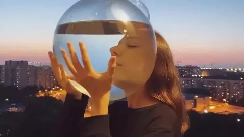 AI Video from prompt: The girl puts a transparent round aquarium with 