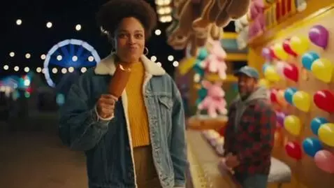 AI Video from prompt: Carnival night, string lights. A woman eats a ve