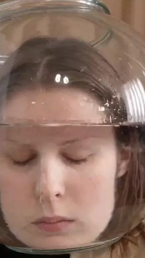 AI Video from prompt: A girl puts a transparent round aquarium with wa