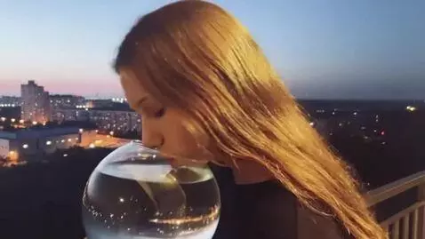 AI Video from prompt: The girl is holding a transparent round aquarium
