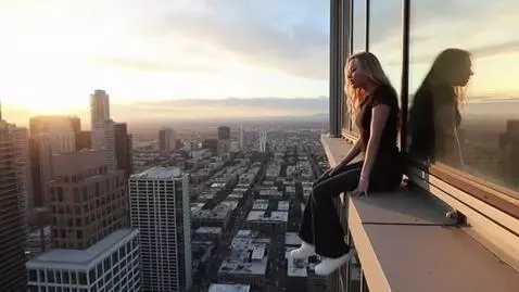 AI Video from prompt: a giant girl sitting on a skyscraper with her le