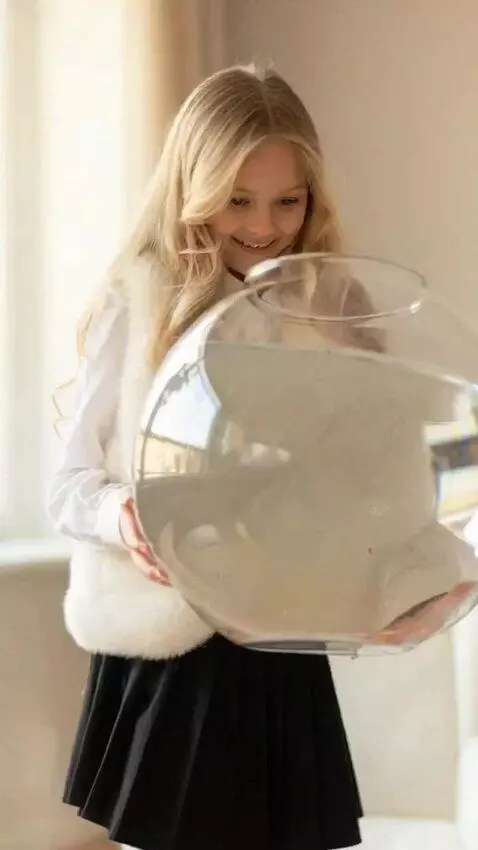 AI Video from prompt: The girl is holding a transparent round aquarium