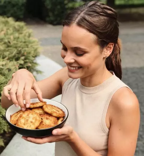 AI Video from prompt: the girl takes one potato pancake from the bowl 