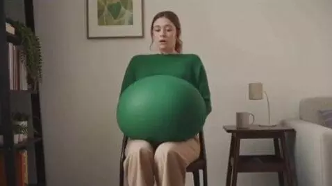 AI Video from prompt: a woman sit on a chair then her belly inflation 