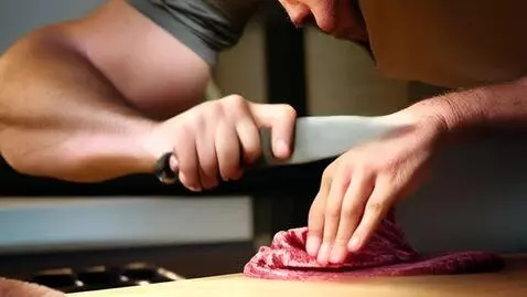 AI Video from prompt: a man cuts meat on a board