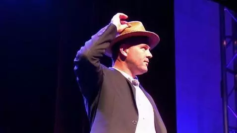 AI Video from prompt: A man takes off his hat on stage