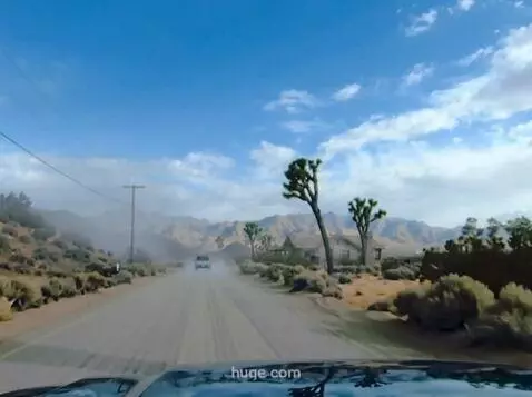 AI Video from prompt: the vehicle moves forward down a dusty Joshua Tr