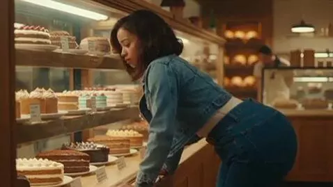 AI Video from prompt: a woman at a bakery looking at cakes. suddenly h