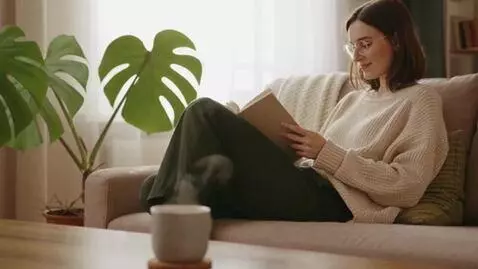 AI Video from prompt: Woman is sitting at home reading her book as her