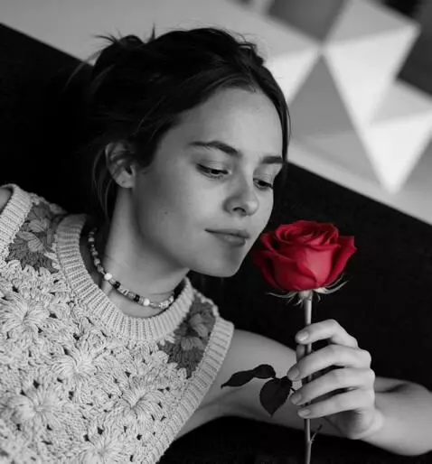 AI Video from prompt: the girl gently brings the rose to her face and 