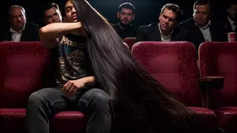 AI Video from prompt: The young man flips his massive hair back, inten