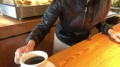 AI Video from prompt: she puts a coffee on the counter. her chest slow