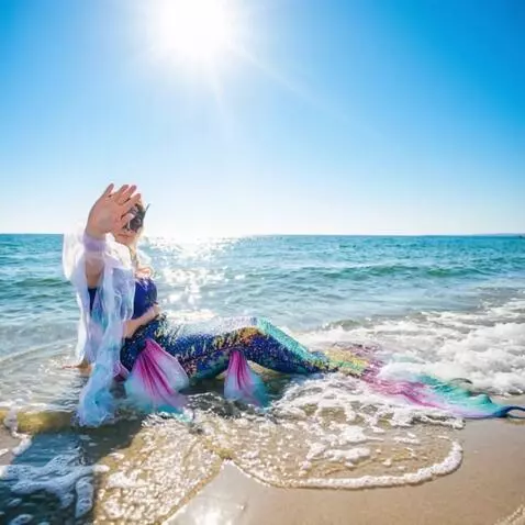 AI Video from prompt: The mermaid sits and waves affably at the camera