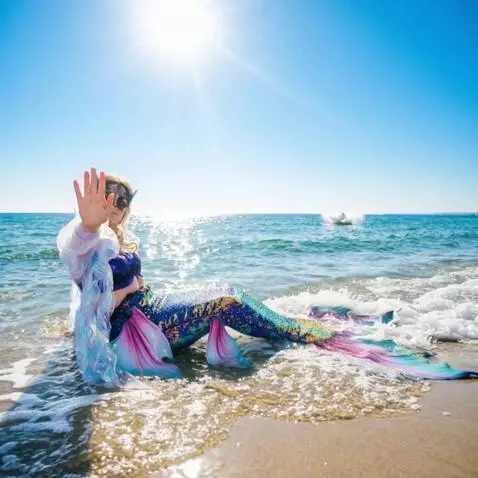 AI Video from prompt: The mermaid sits and waves affably at the camera