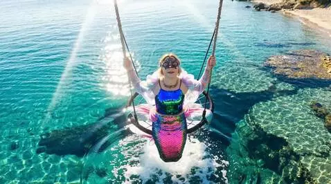AI Video from prompt: A mermaid is swinging on a swing above the surfa