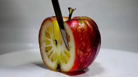 Ultra close-up of a knife slicing a hyper-realistic apple, revealing a yellow lemon-like interior.