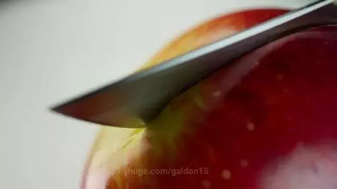 Ultra close-up of a knife slicing a hyper-realistic apple in slow motion against a white background.