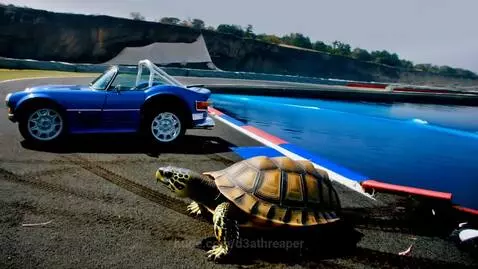 A bright blue classic Jaguar xj parked on a race track with a large turtle walking across the asphalt.