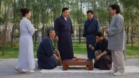 Group of people dressed as samurai and ninjas in traditional robes gathered around a table outdoors.