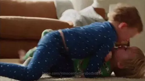 Two toddler boys in pajamas fighting and wrestling on a carpeted floor.