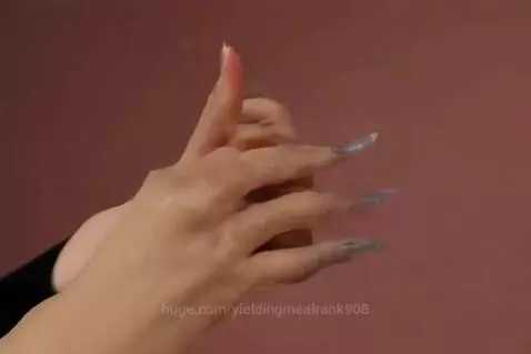 Close-up of a hand cutting a transparent glass chess queen with a large knife on a black cutting board.