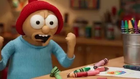 Claymation character with red beanie, angry expression, sitting at a table with scattered crayons and a drawing.