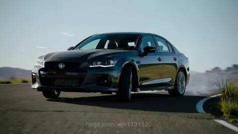 Dark grey sedan drifting on a paved road, rear tires smoking, with hills in the background.