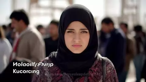 Uyghur woman in traditional headscarf smiling softly in warm lighting.