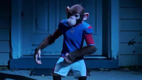 Monkey wearing a blue and red football shirt dancing energetically in front of a door at night, doorbell camera footage.