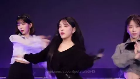 Three K-pop girl idols in Y2K outfits dancing on a purple-lit stage.