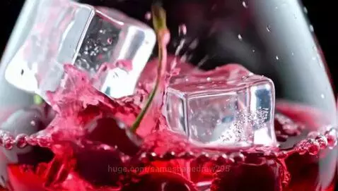 Close-up slow-motion of dark red cherries and ice cubes falling into red liquid, creating dynamic splashes.