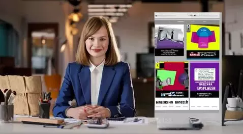 Young woman with black bob haircut in a business suit smiling at a modern desk with web development code on screen.