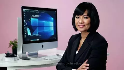 Confident Russian woman with bob haircut at desk, web development visuals on screen, smiling.