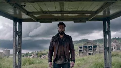 Rugged, bearded man stands determined in front of city ruins under a dark, stormy sky with swirling debris.