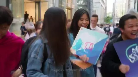 Young people in a busy city street handing out PCMAGNAAT tech gadgets and laptops.