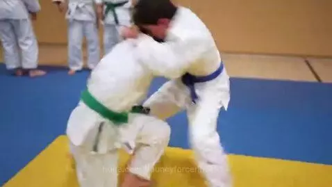 Two boys in judogi grappling and rolling over each other during a judo practice session.