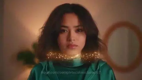 Young woman with dark wavy hair smiling broadly in a dark green top, after a transformation.