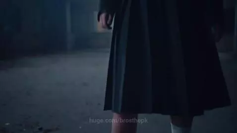 Ghostly young woman in a dark school uniform stands in front of a foggy, dilapidated college hostel at night.