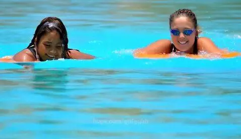 Two young women tubing down a river on a sunny day, smiling and enjoying the water.