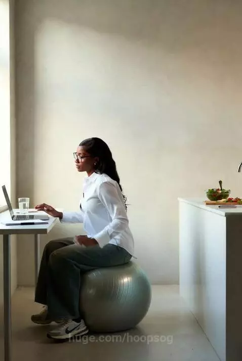 Woman working on a laptop on an exercise ball, then preparing a fresh salad in a modern kitchen.