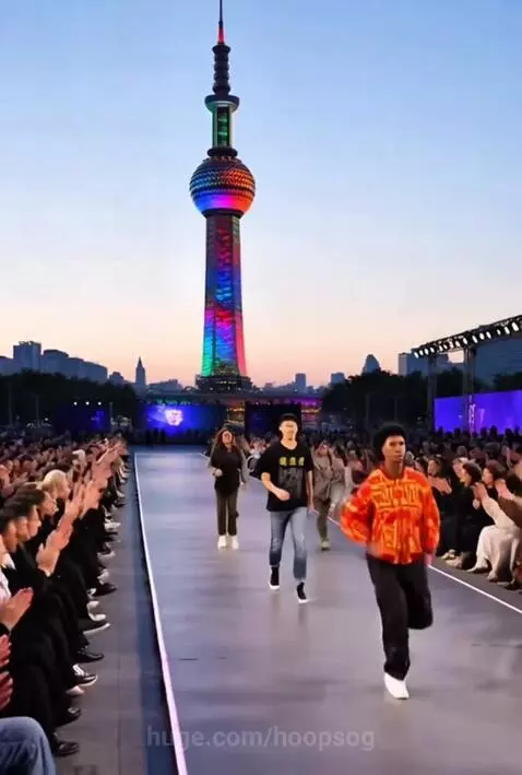 Outdoor fashion show with models on a runway, Shanghai's Pearl Tower illuminated in the background.