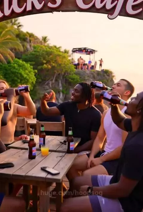 Adults cheering and toasting drinks at Rick's Cafe during a sunset cliff dive into the ocean.