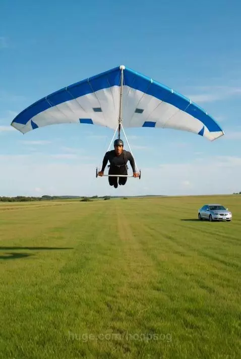 Person in hang glider landing in a field and running to a car to drive away.