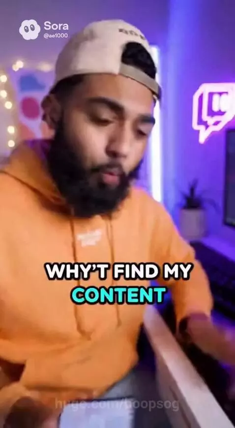 Man with beard and cap in orange hoodie, holding phone with raccoon app, looking at camera in neon-lit room.