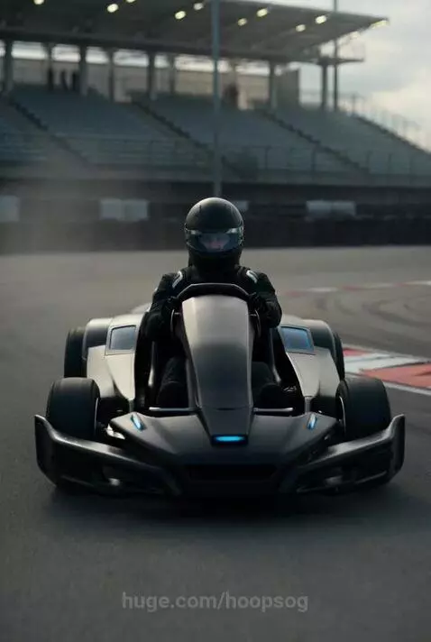 Person in black racing suit driving a black go-kart with blue accents on a race track, navigating a turn at speed.