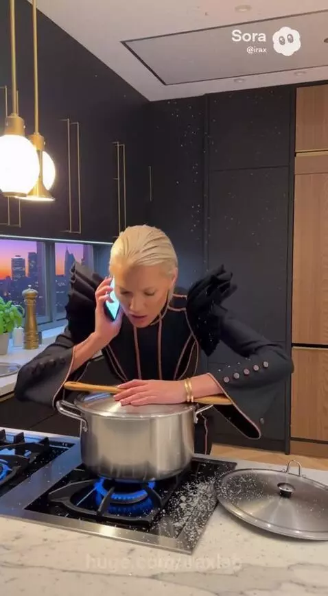 Woman in a black dress screams as a snake drops into her cooking pot in a modern kitchen.
