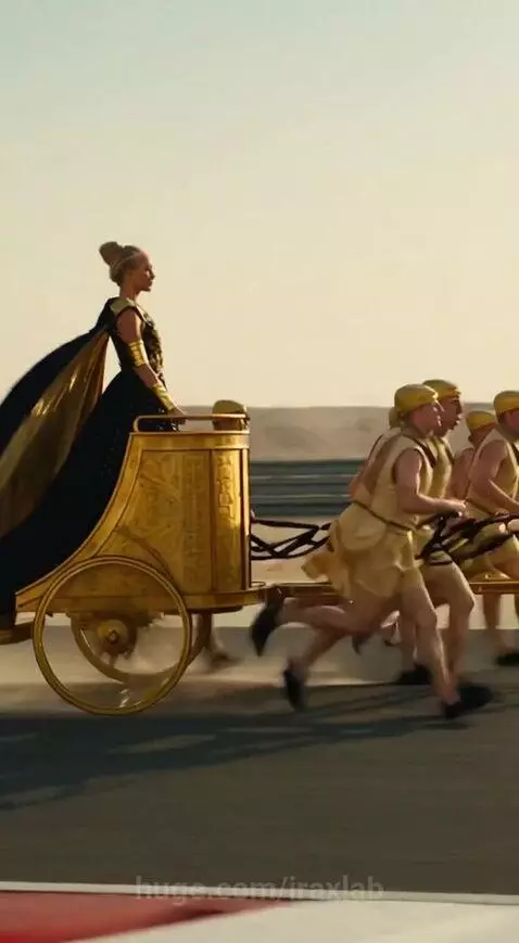 Woman in gold chariot pulled by runners races on desert track against a motorcycle.