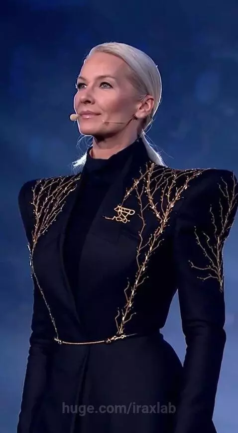 Speaker on stage with blue and purple lighting, addressing an enthusiastic audience. Confetti falls.